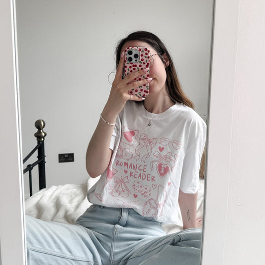 Person wearing a white t-shirt with text and graphics, standing in front of a mirror.