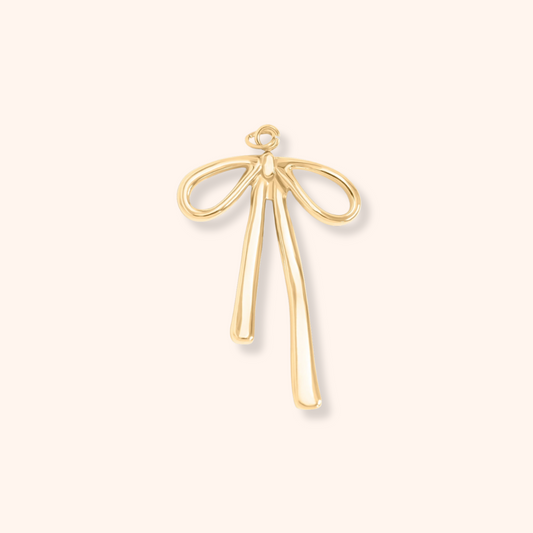 Gold bow-shaped pendant on a light beige background