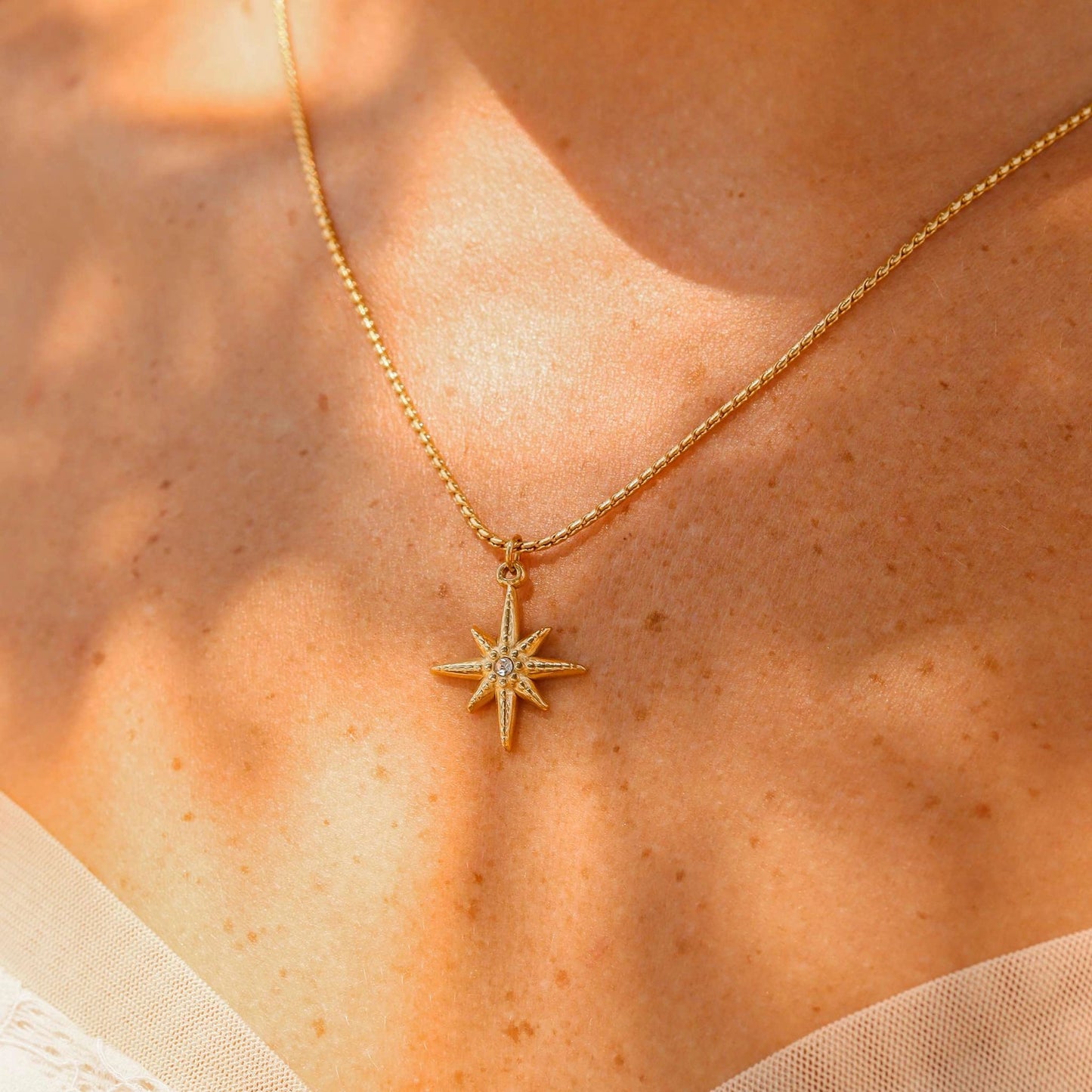 Gold necklace with a star-shaped pendant on a person's neck