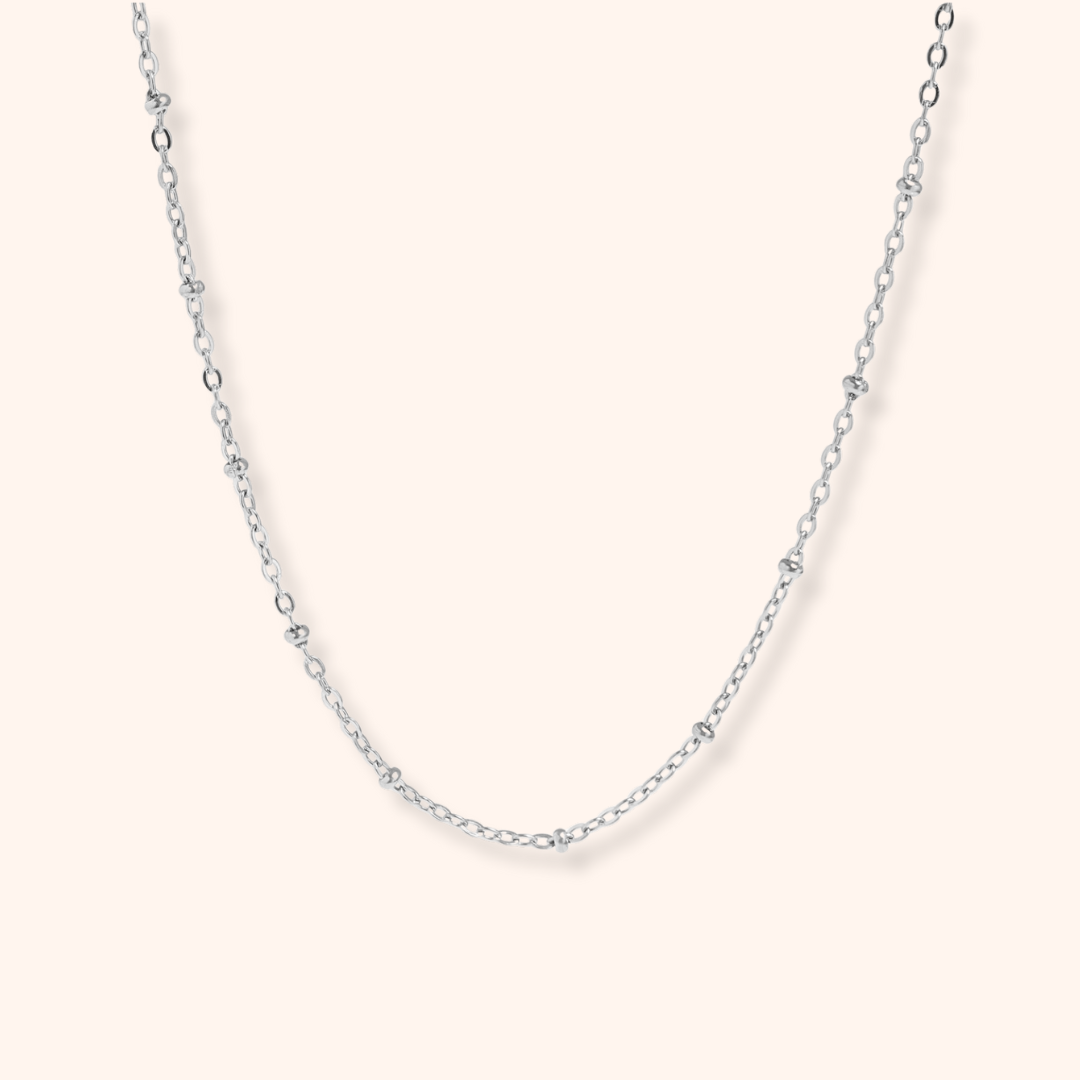 Silver chain necklace on a light pink background