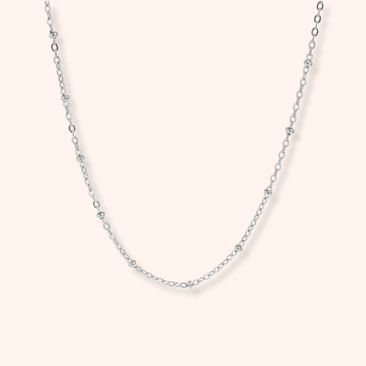 Silver chain necklace on a light pink background