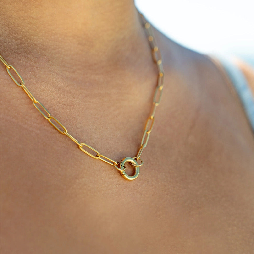 Gold chain necklace on a person's neck with a blurred background