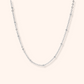 Silver chain necklace on a light pink background