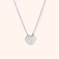 Silver necklace with a round pendant on a light gray background